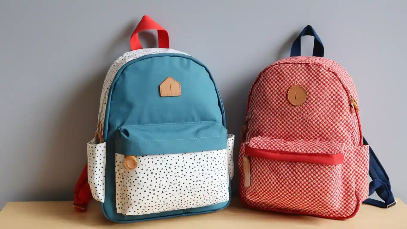Sac a dos maternelle coloré pour enfants, avec une poche avant et des bretelles ajustables, sur un fond pastel.